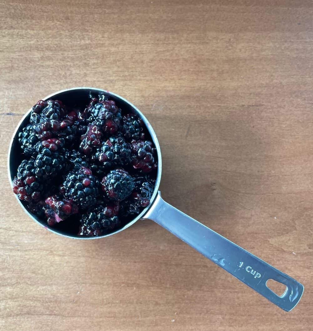 a measuring cup full of blackberries