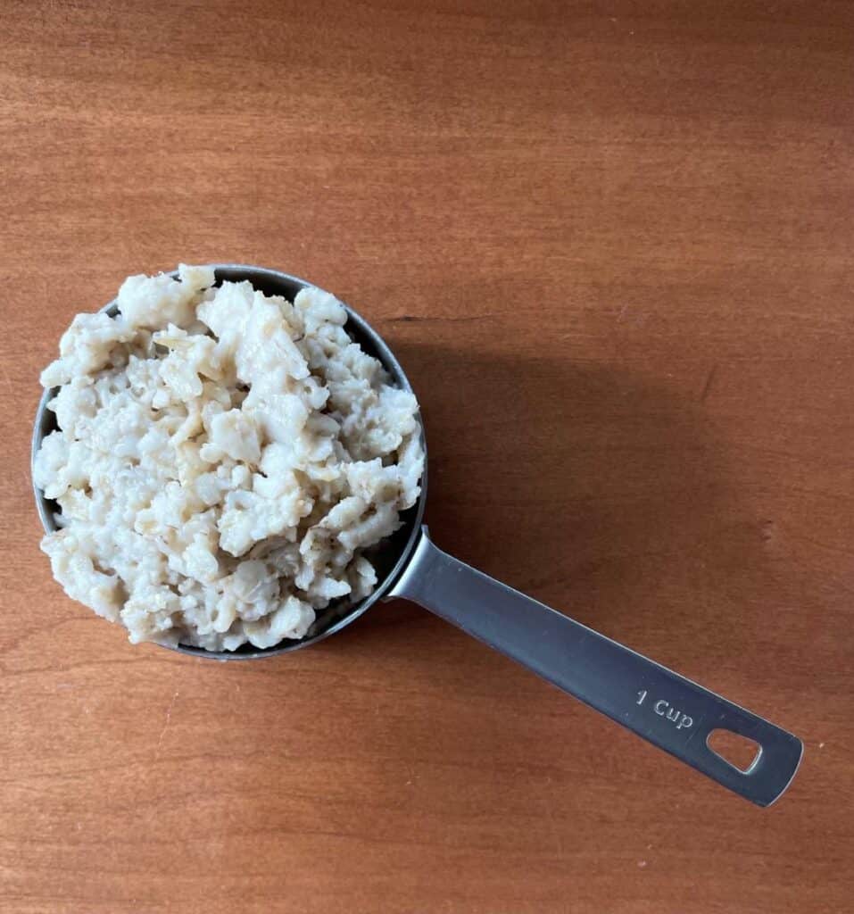 a one cup measuring cup full of cooked oatmeal.