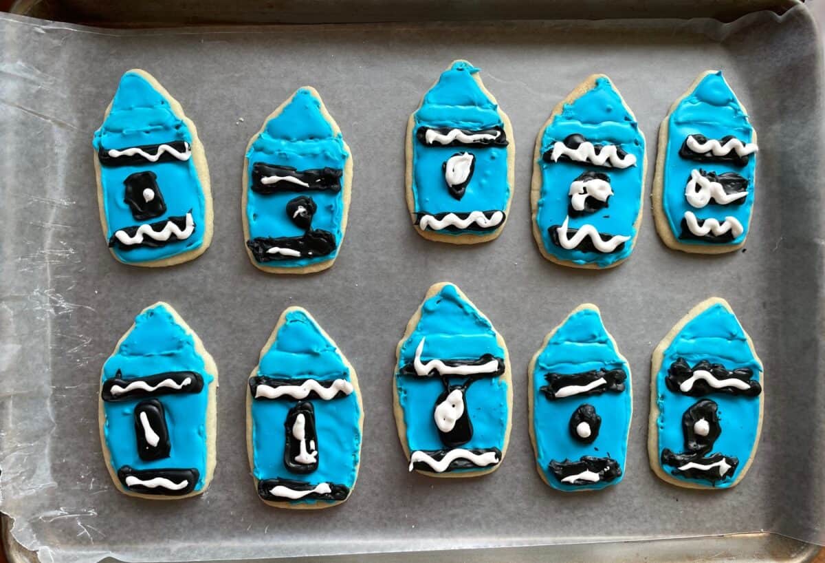 a tray of 10 crayon shaped cookies decorated with blue royal icing