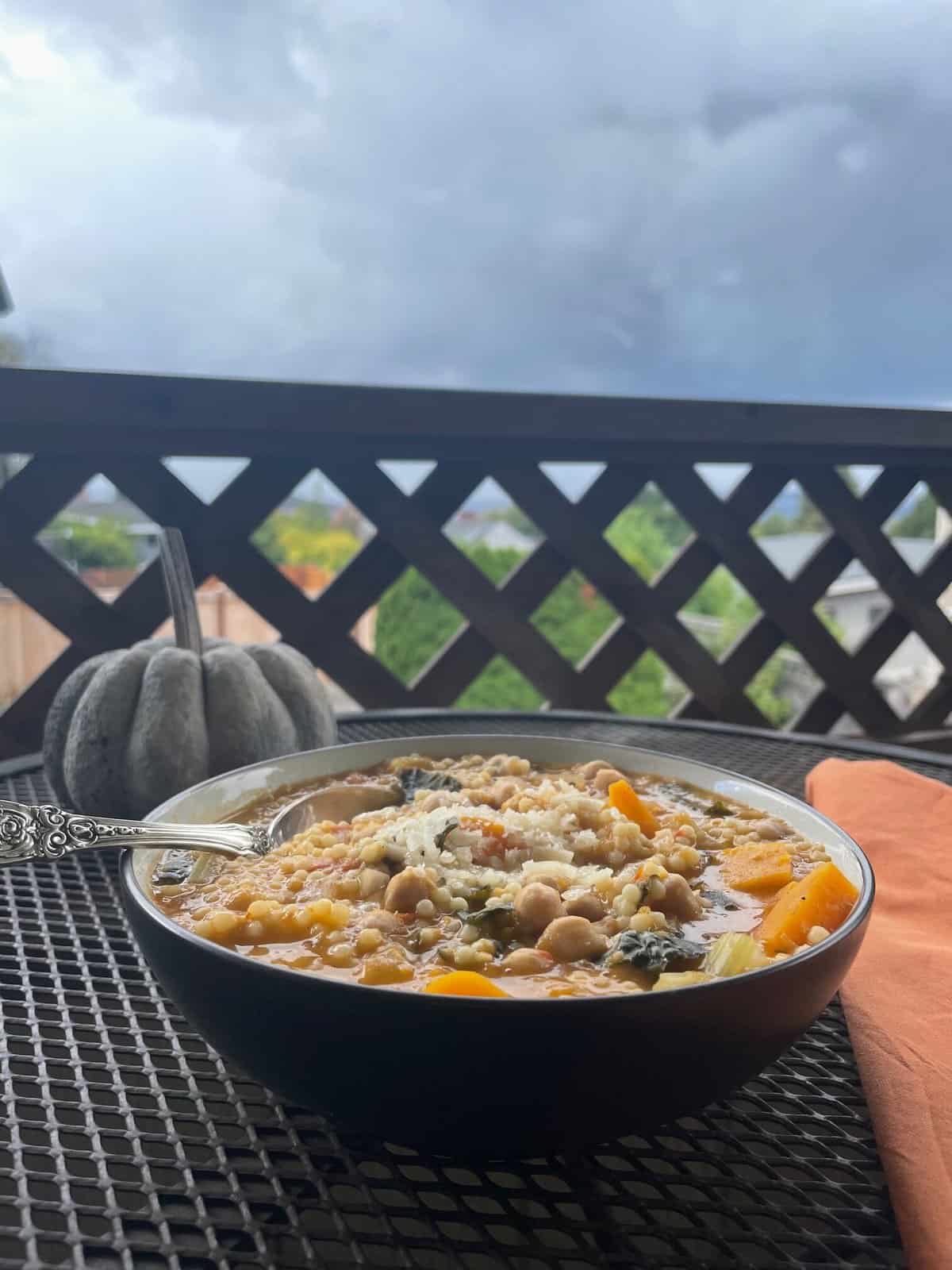 steaming bowl of garbanzo bean soup with pumpkin and cloudy day in background.