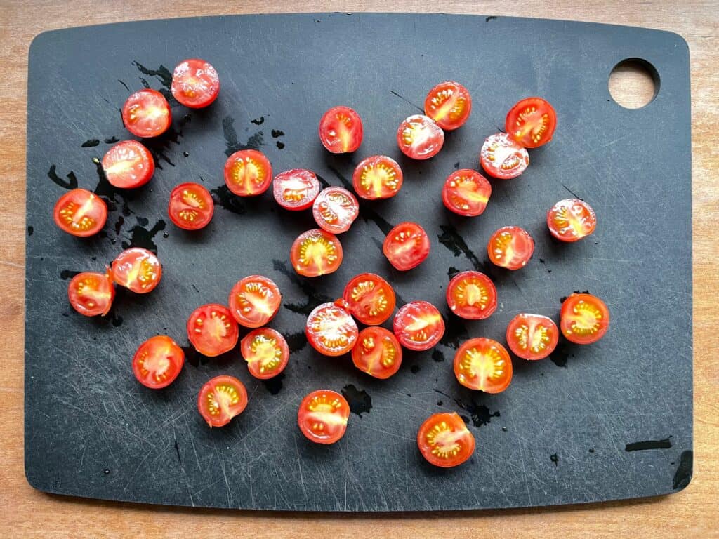 cherry tomato halves on a cutting board.