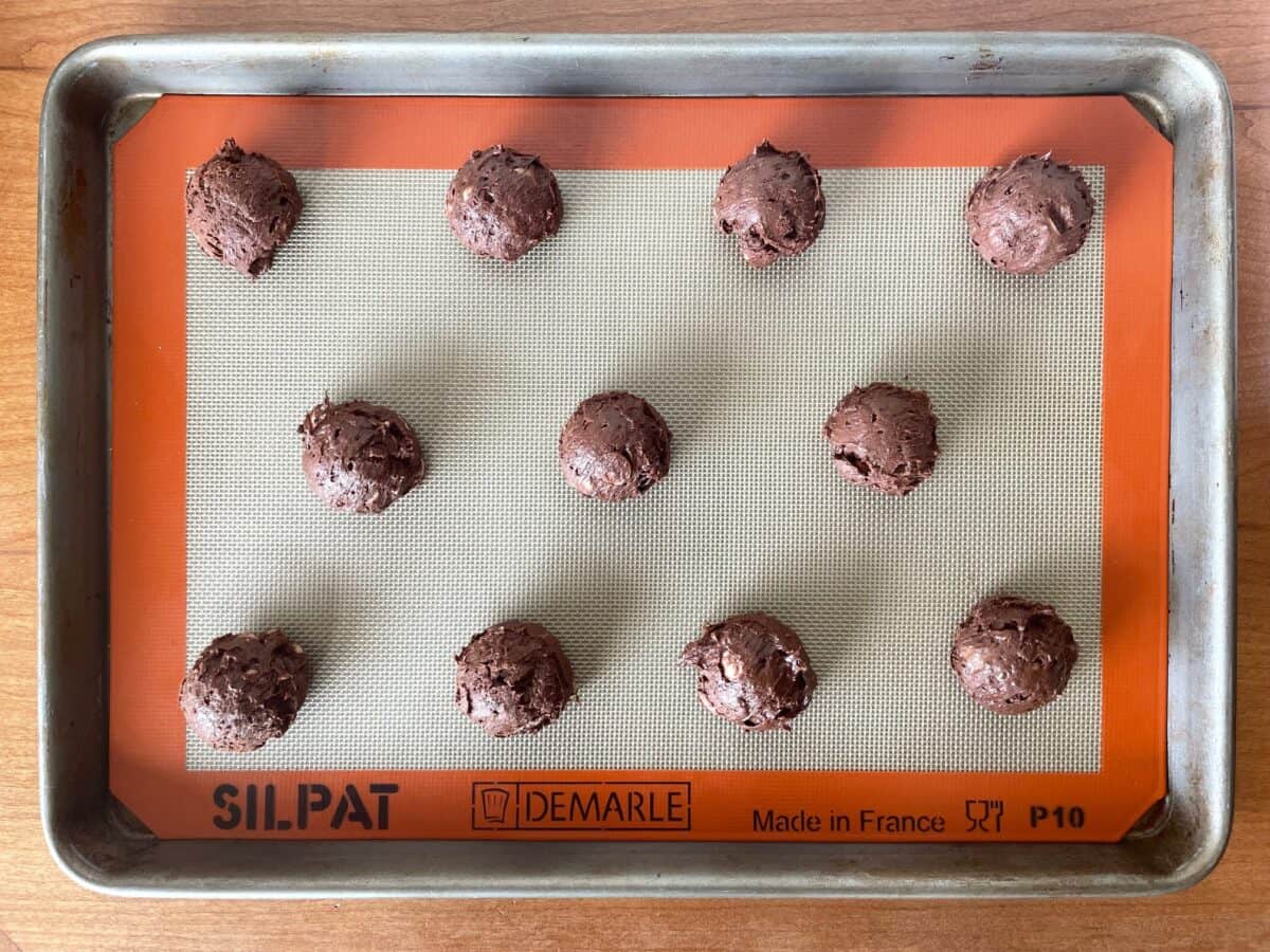 a baking sheet with 11 balls of raw cookie dough.