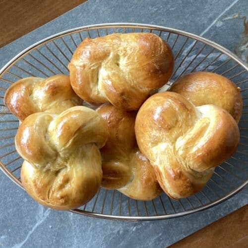 braided challah buns in a wire basket.