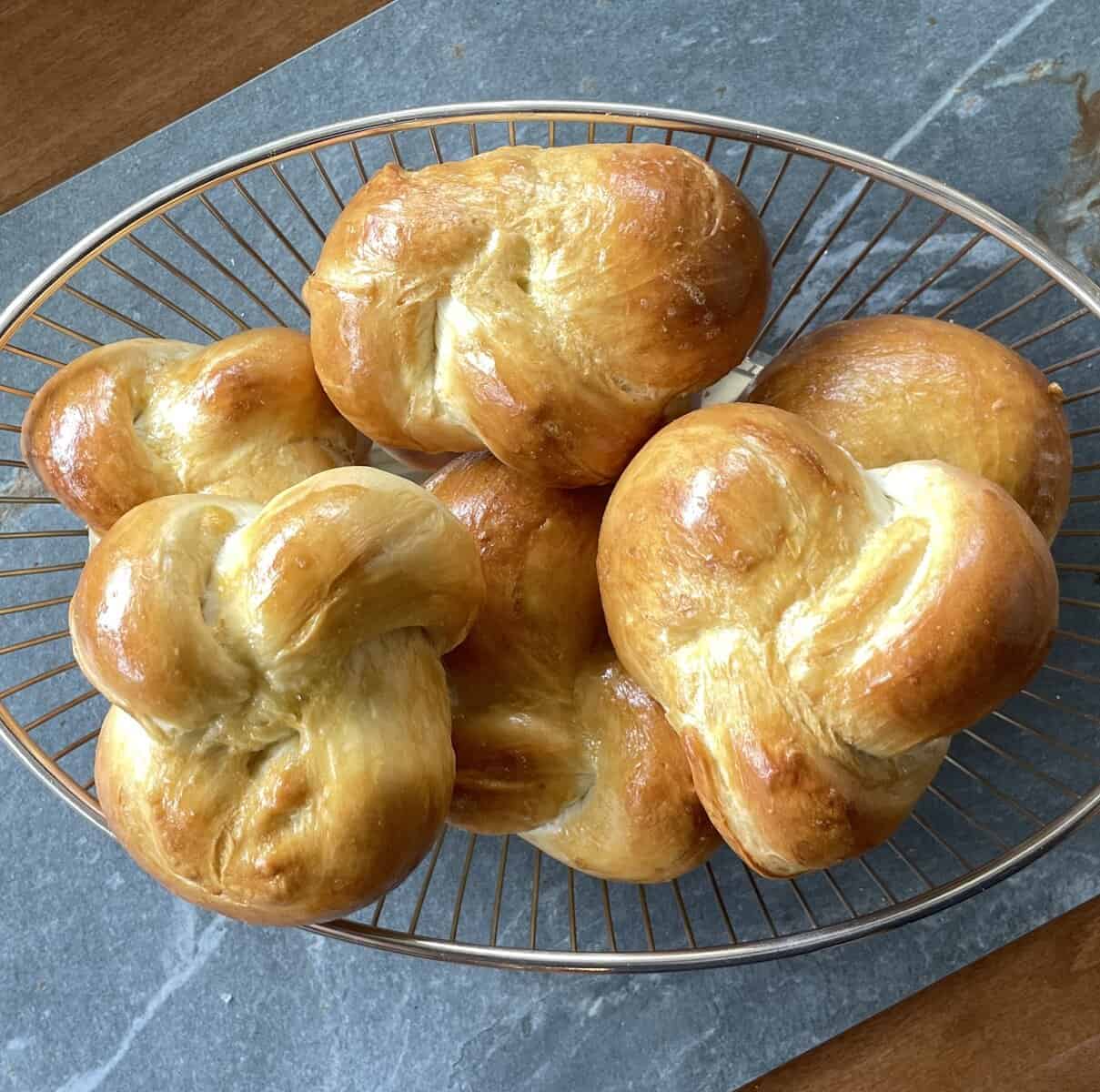 braided challah buns in a wire basket.