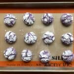 a baking sheet filled with ube crinkle cookies.