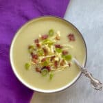 a bowl of 4 ingredient potato soup garnished with bacon, cheese, and scallions.