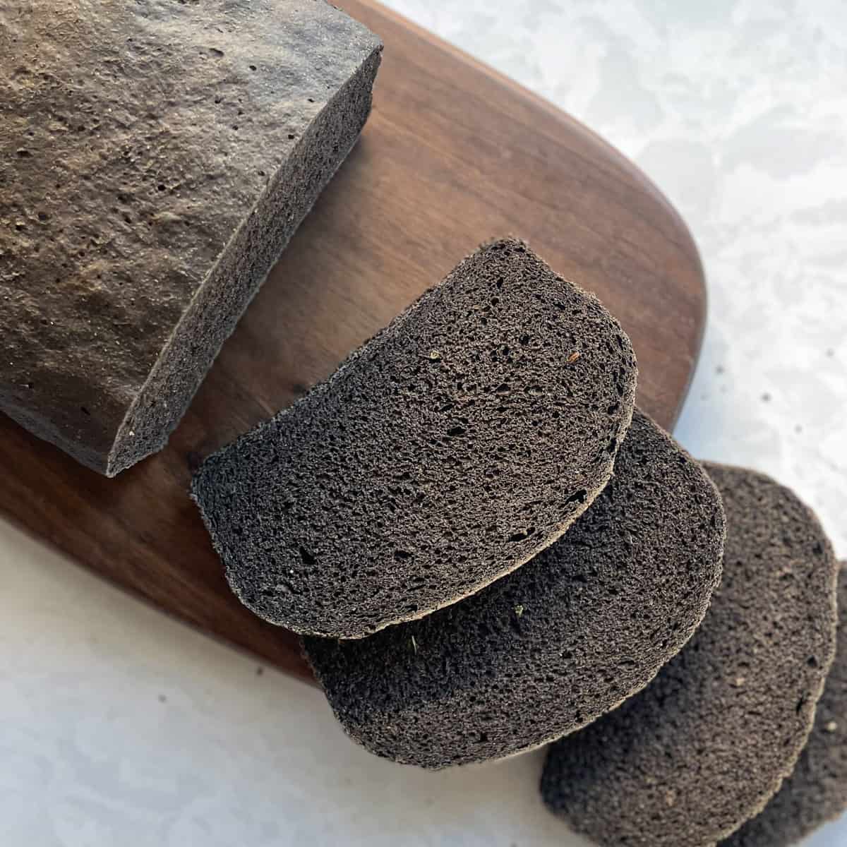 sliced loaf of black russian rye bread on a cutting board.