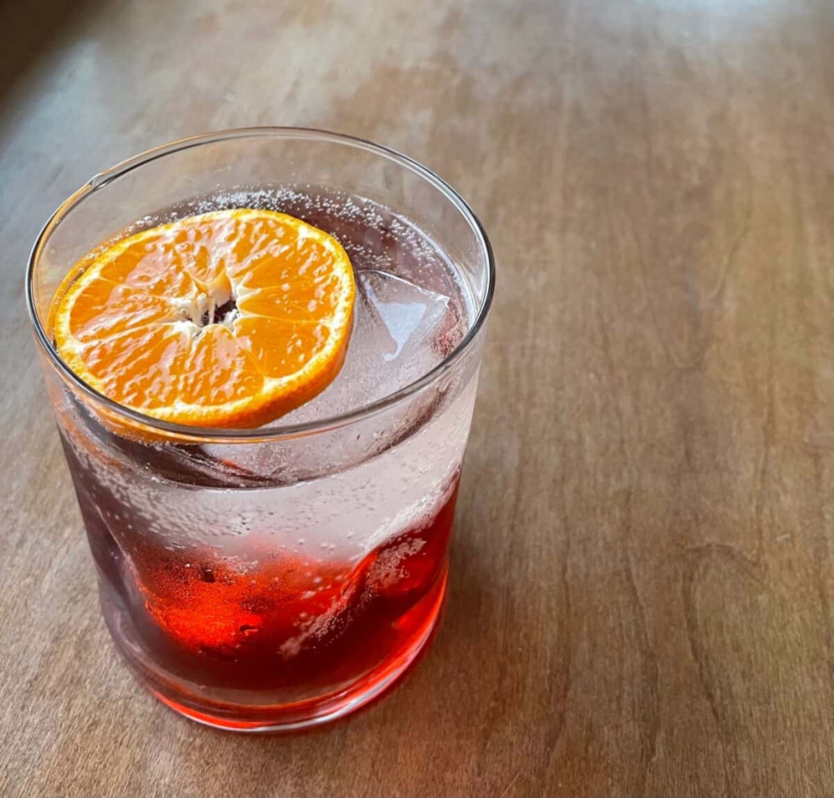 a lowball negroni spritz garnished with an orange slice.