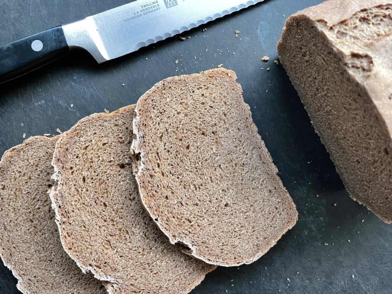 sliced loaf of Russian rye sandwich bread and knife on a cutting board.
