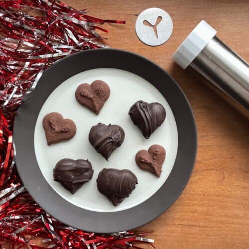 a plate of chocolate peppermint spritz cookies with a cookie press and disk