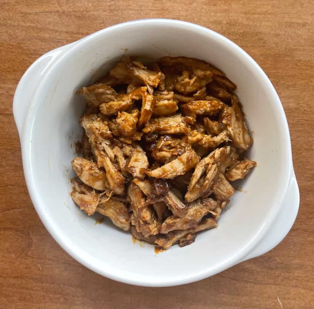 a bowl of pulled pork mixed with hoisin sauce.