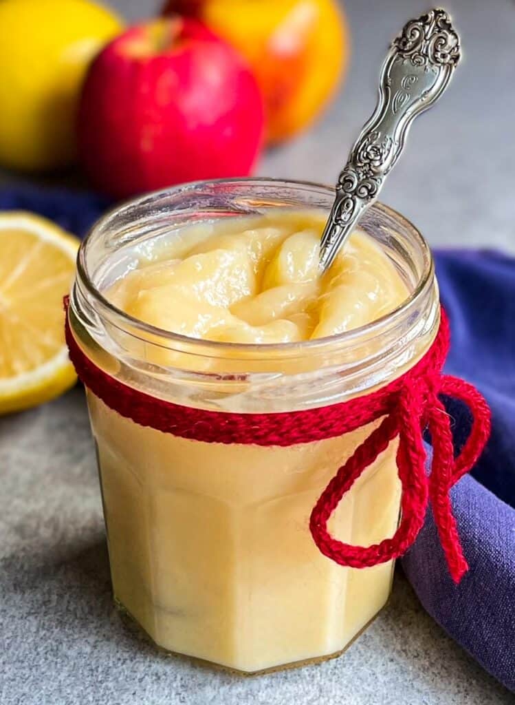 a jar of lemon apple curd with a spoon.