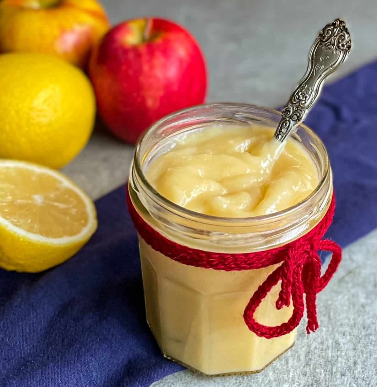 lemon apple curd in a jam jar with a spoon.