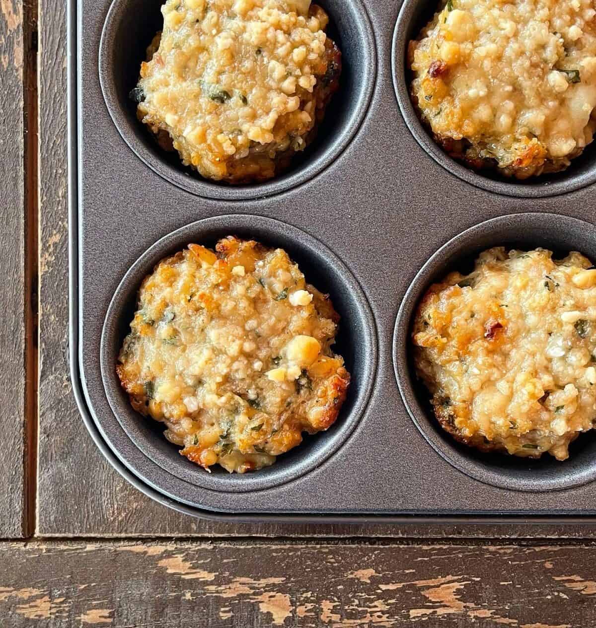 a muffin tray containing baked parmesan crusted chicken muffins.