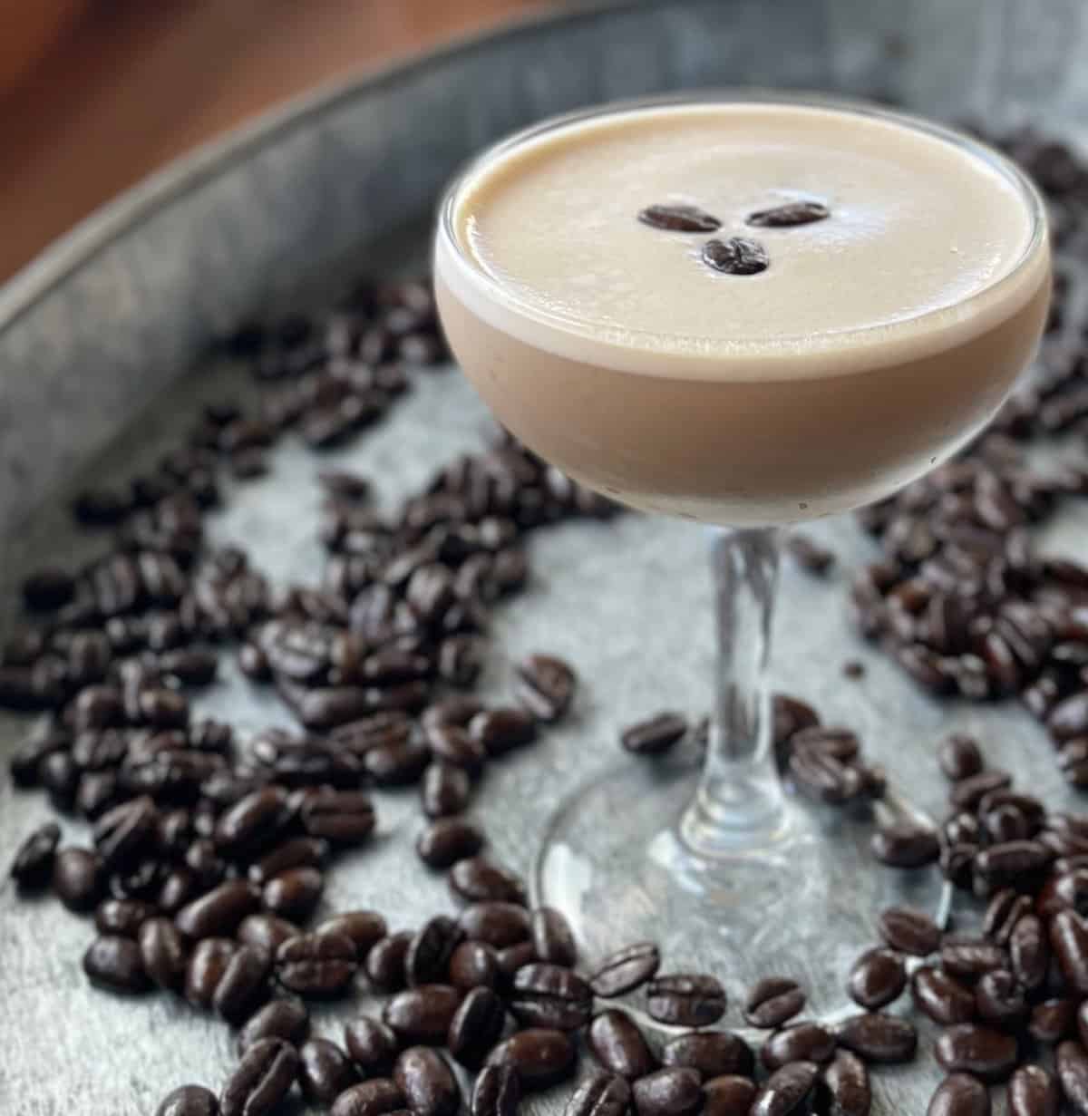a creamy espresso martini with Baileys on a tray of coffee beans.