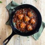 a cast iron pan filled with chicken meatballs and barbecue sauce.