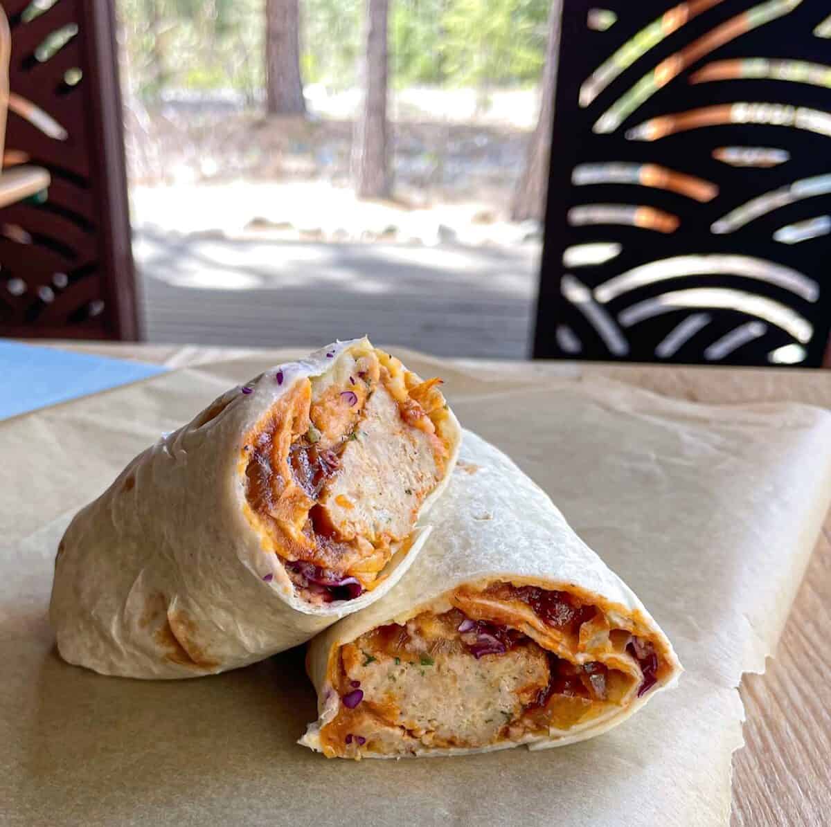 a meatball wrap on a picnic table with trees in the background.