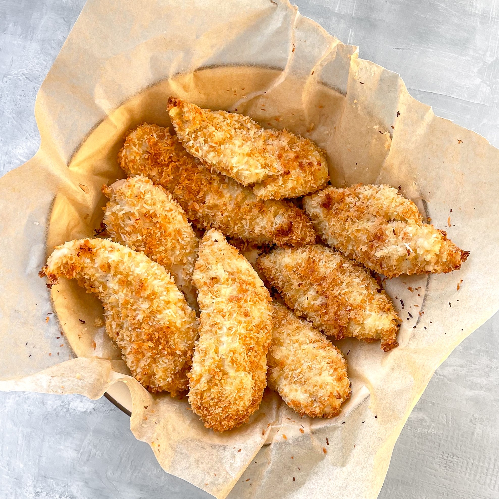 bowl of crispy brown panko chicken tenders in brown paper.
