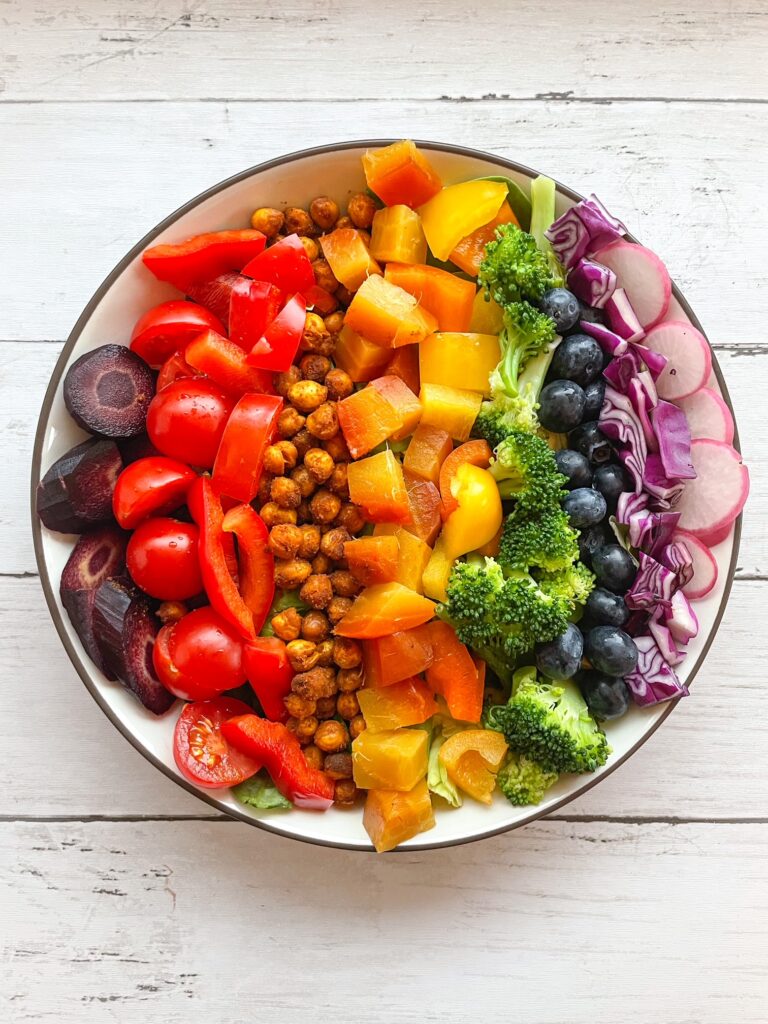 a salad bowl of vegetables arranged in rainbow order.