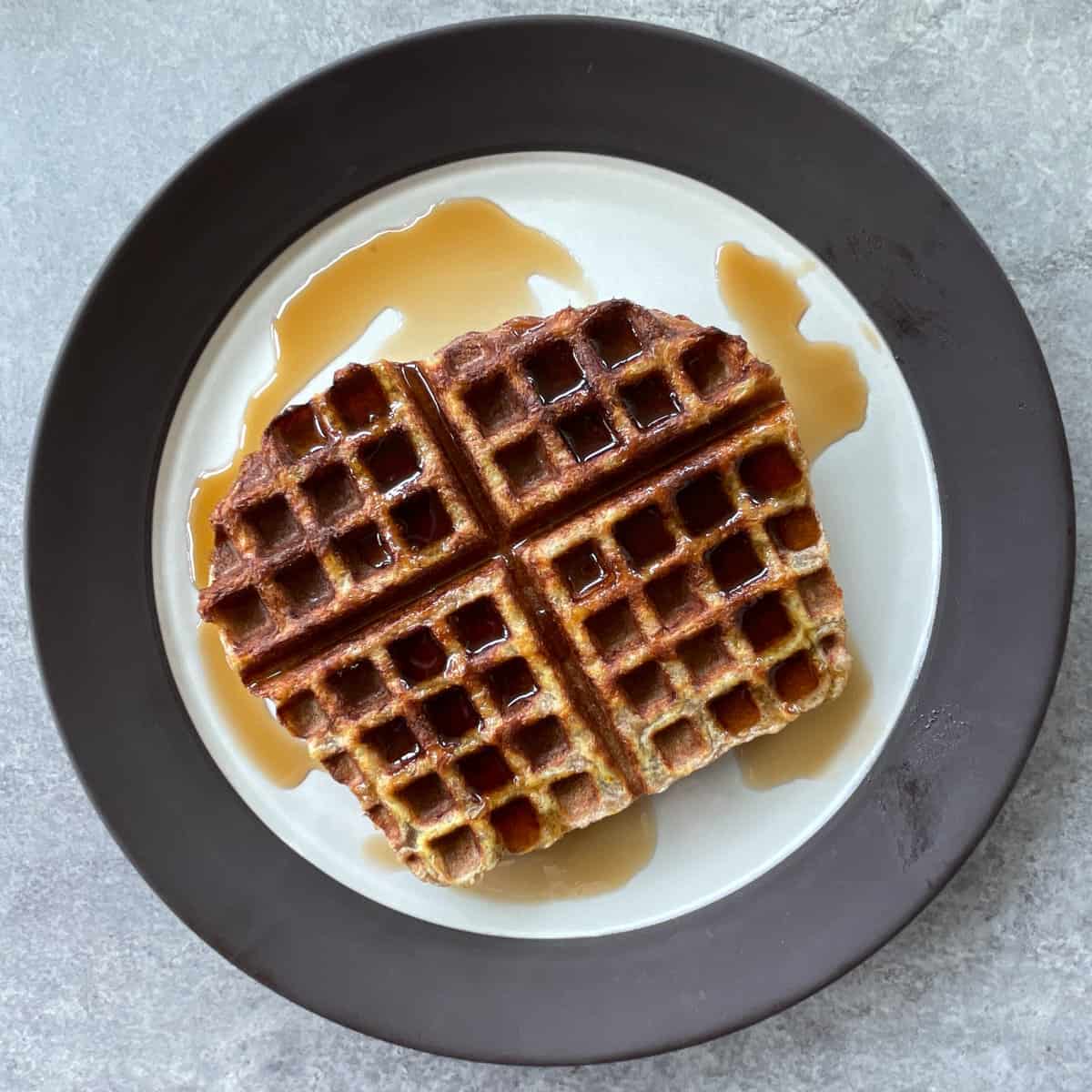 French toast waffle covered in maple syrup on a plate.