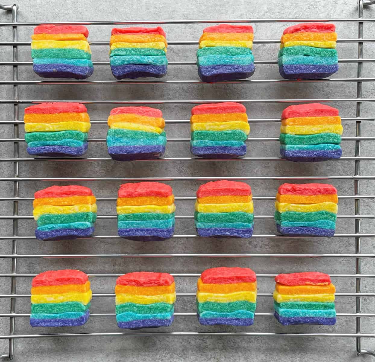 square striped rainbow cookies on a cooling rack.