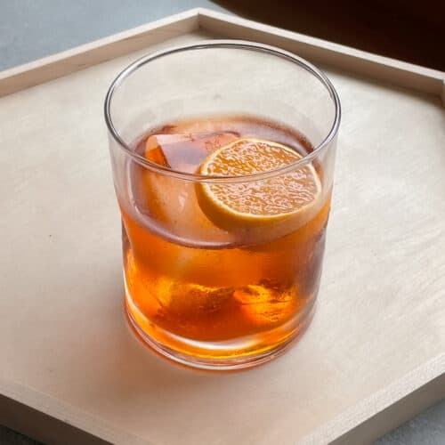 aperol negroni in a rocks glass garnished with orange slice.