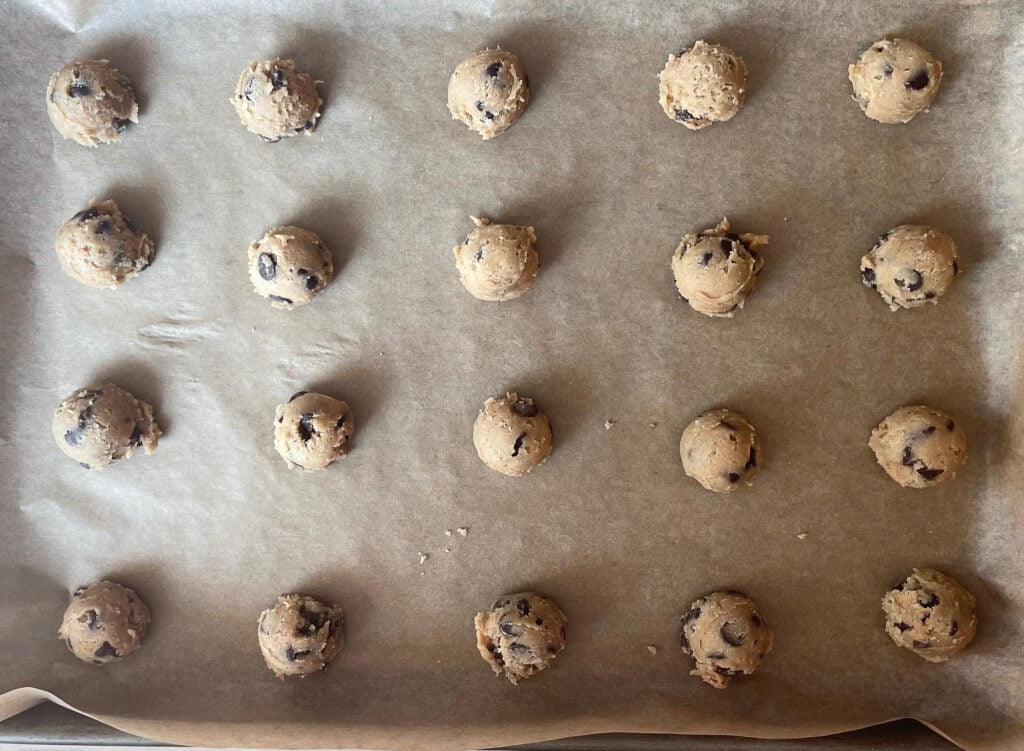 mini chocolate chip cookie balls on a baking sheet lined with parchment.