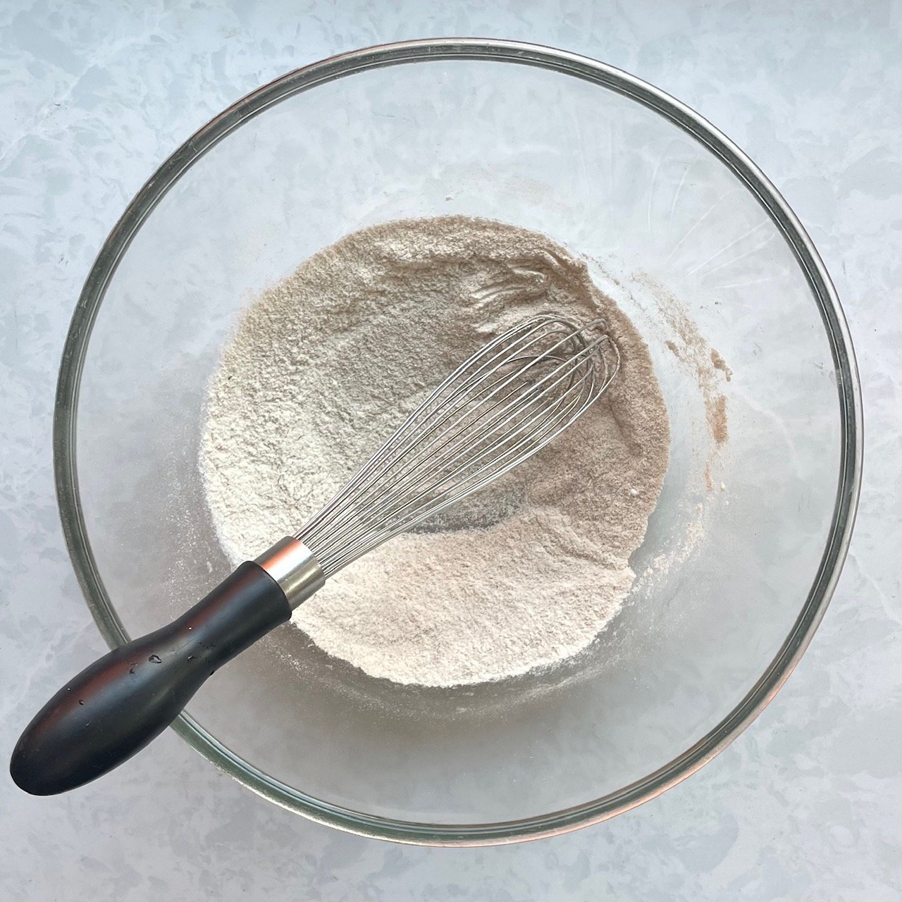 flour and spice powder in a large glass bowl with a whisk.