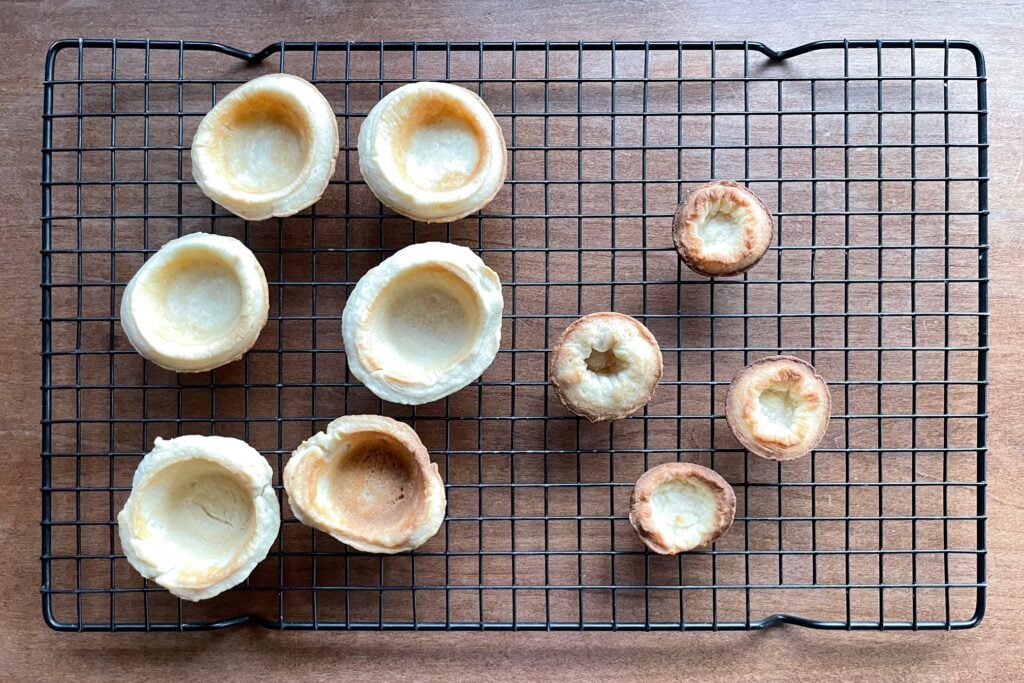 eight misshapen mini pie crust shells on a cooling rack.