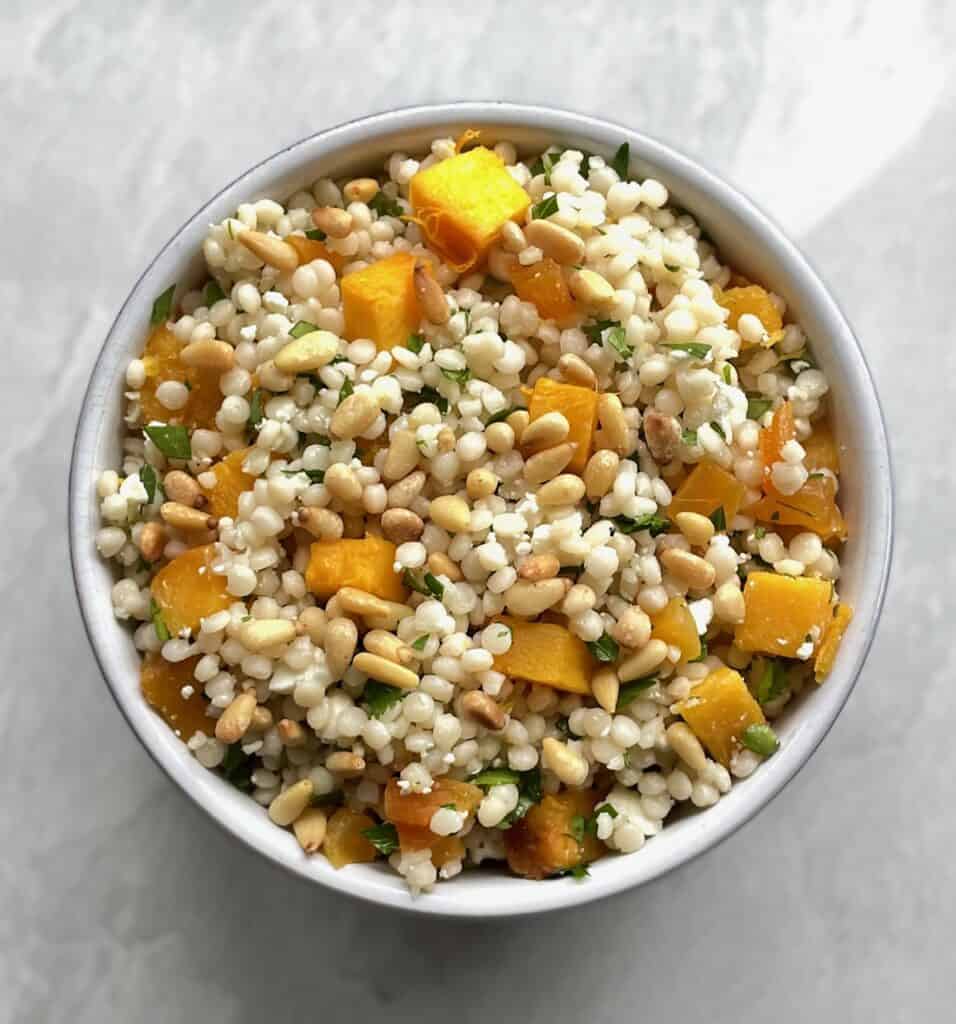 bowl of pumpkin couscous salad with pine nuts and parsley.