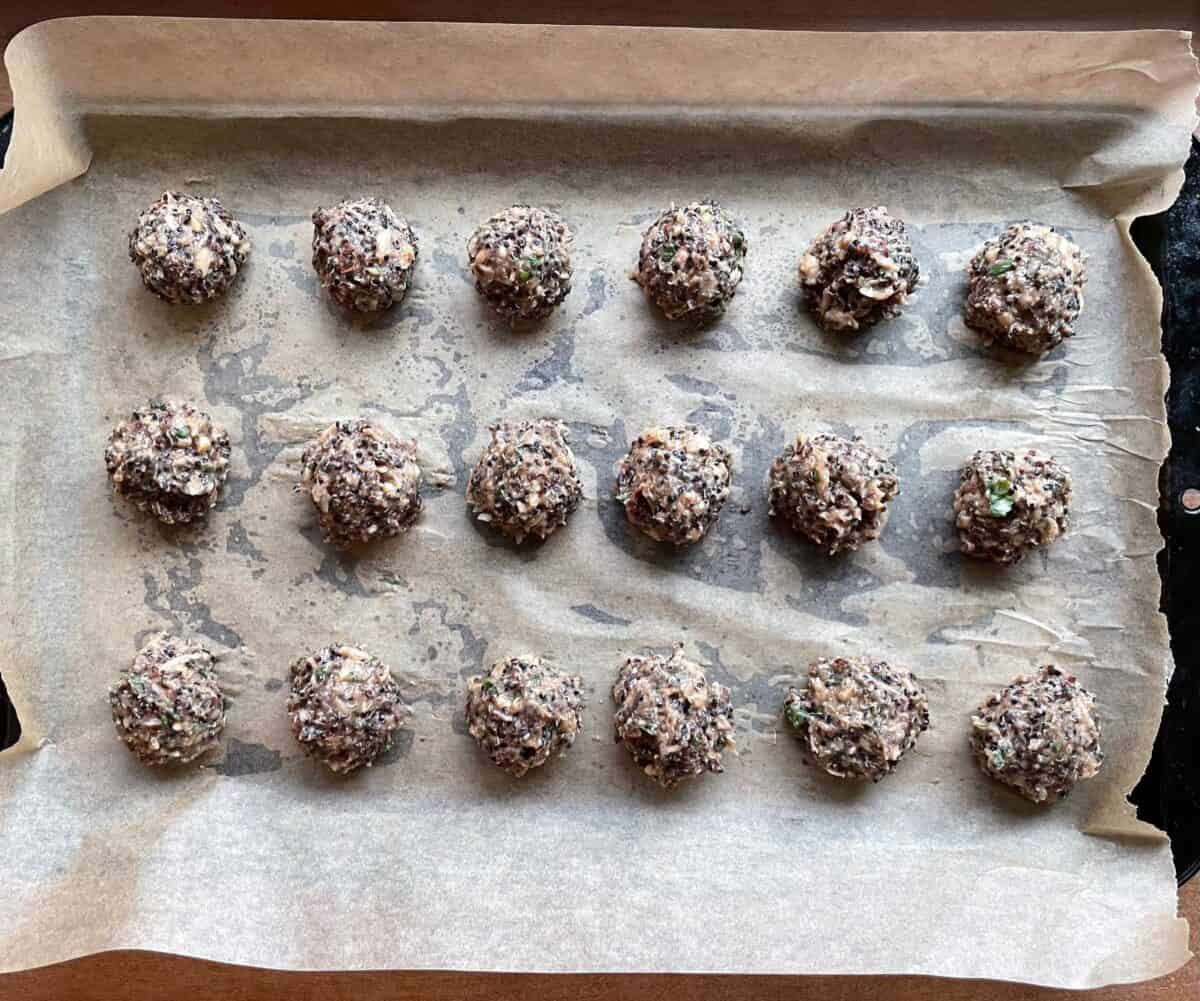 unbaked quinoa balls on a parchment-lined baking sheet.