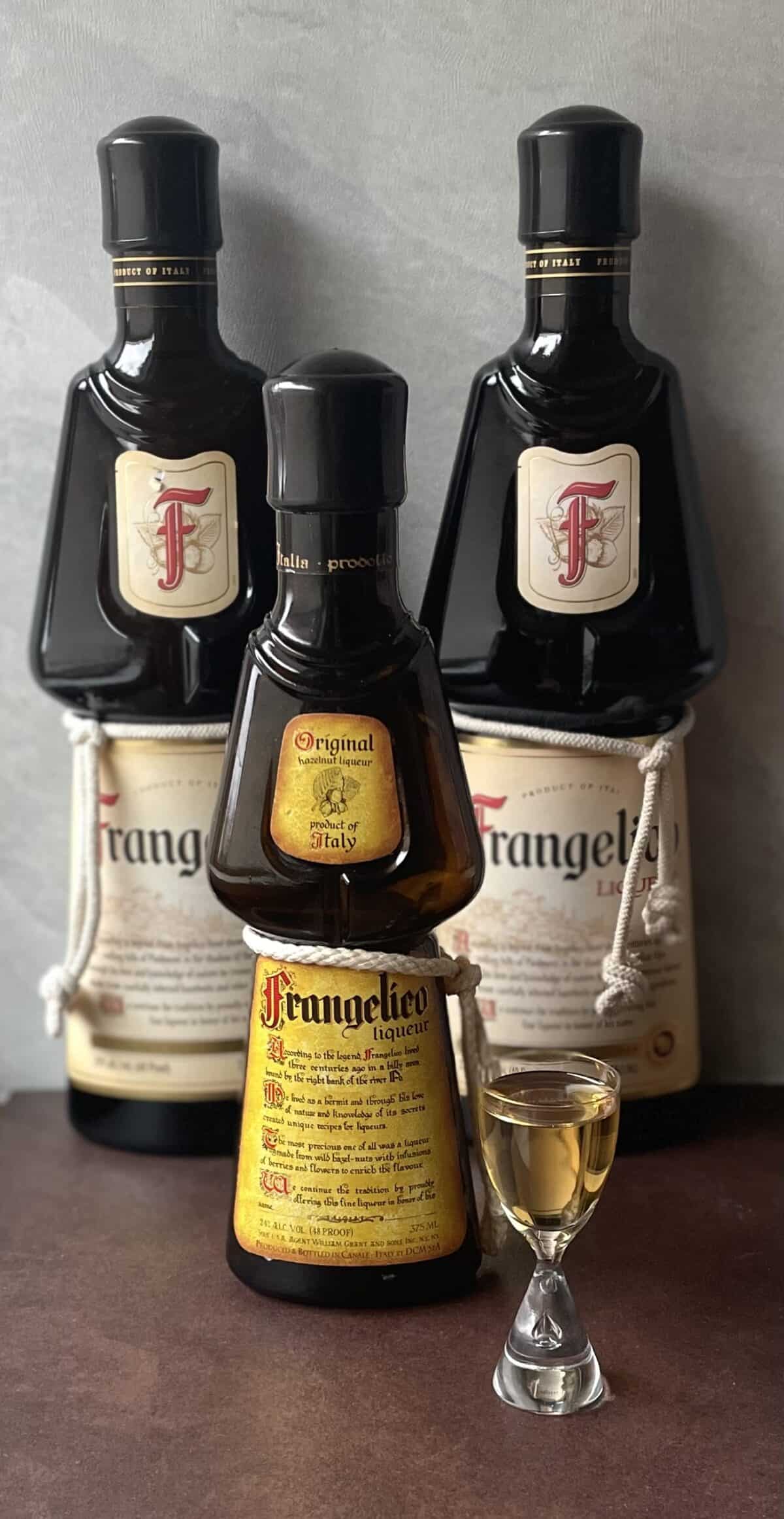 two large bottles of frangelico, a small bottle, and a shot of Frangelico.