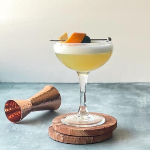 frangelico sour with egg white foam and orange peel and cocktail cherry garnish.