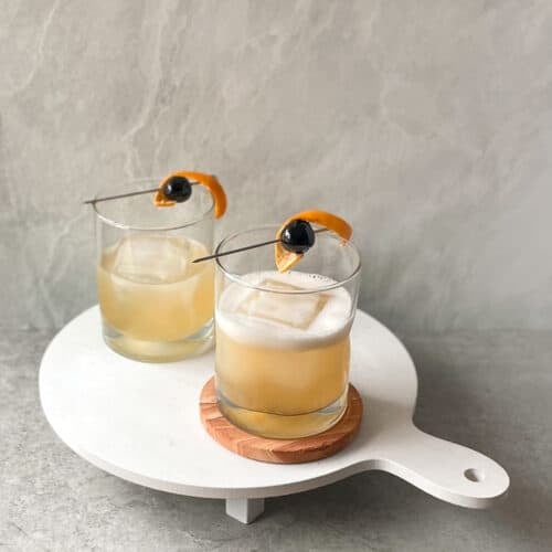 two frangelico sour cocktails in lowball glasses on a white tray.