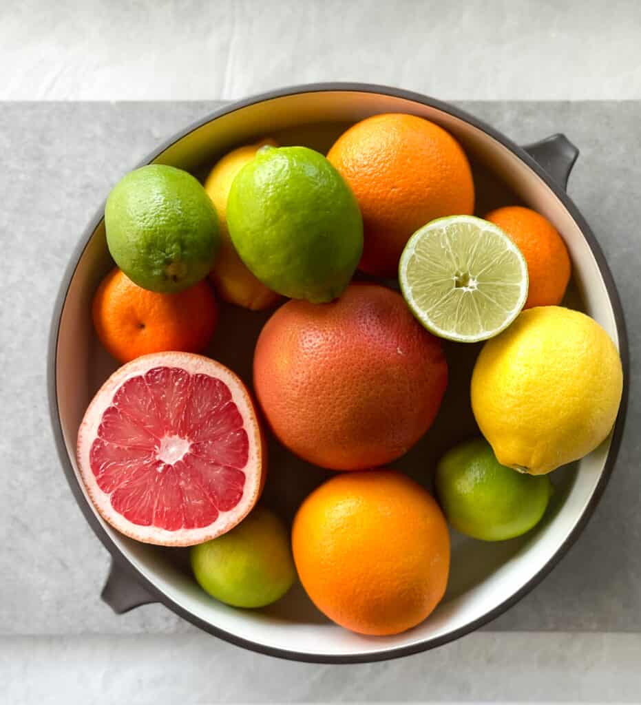 a bowl of citrus fruit including grapefruit, orange, lemon, and limes.