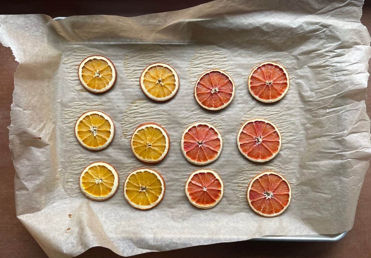 six dried orange slices and six dried pink orange slices on a parchment-lined baking sheet.