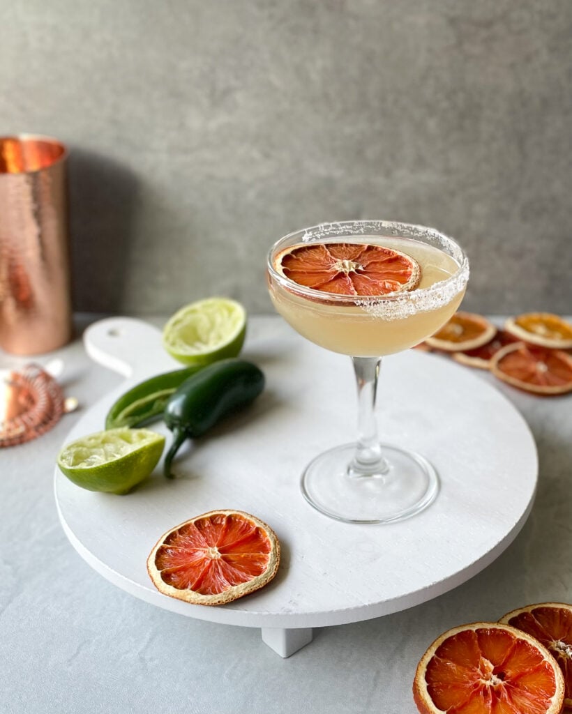 a spicy skinny margarita garnished with dehydrated orange slices with lime and jalapeno halves.