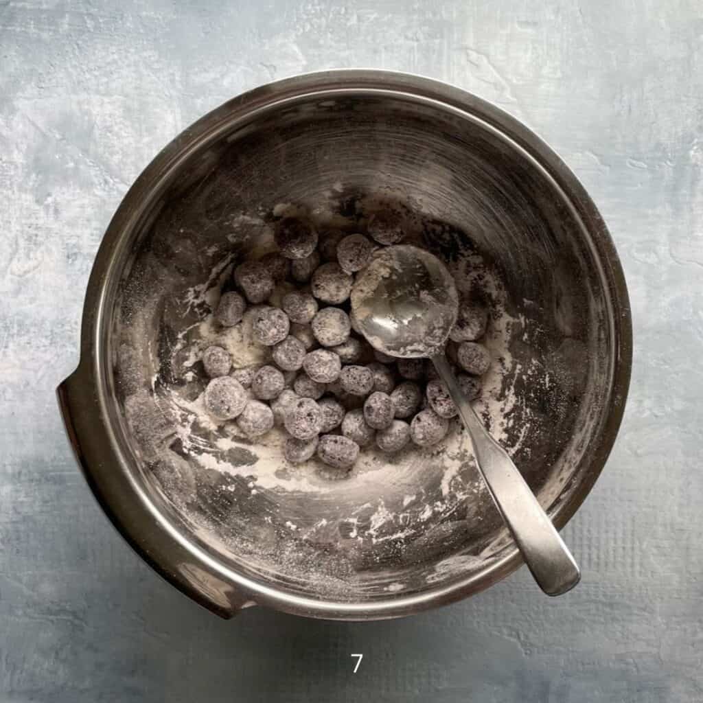 metal bowl with blueberries covered in flour and metal spoon.