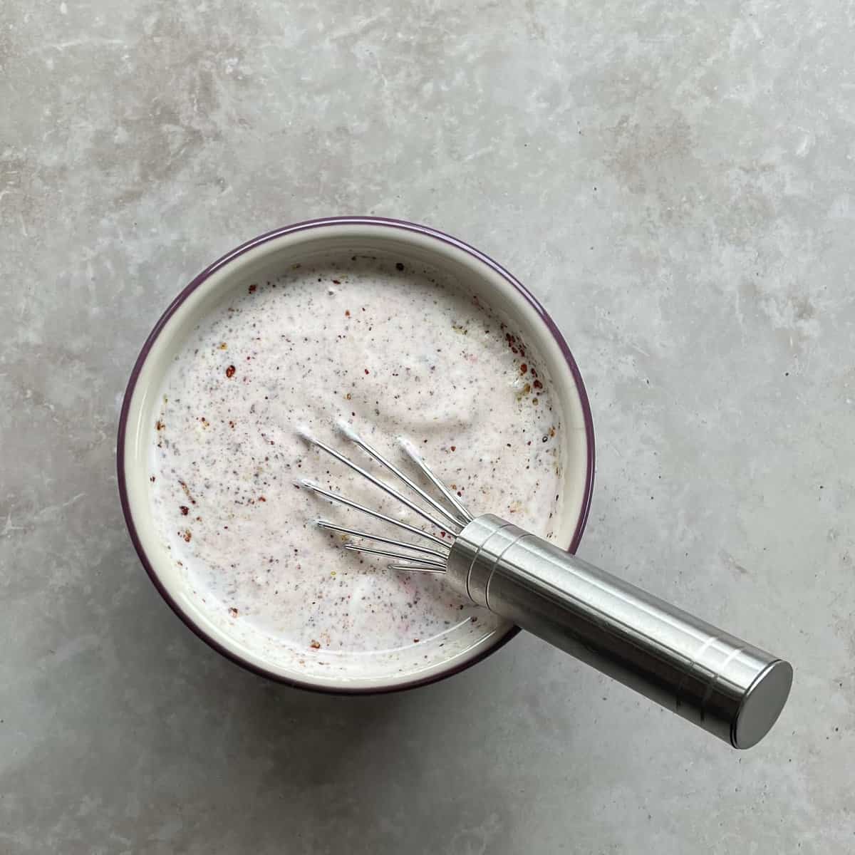 bowl of sumac dressing with whisk.