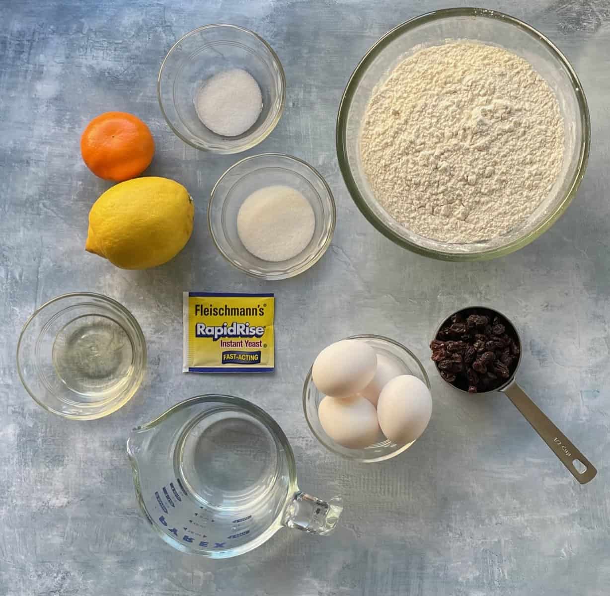 orange, lemon, and other ingredients for the raisin challah on a countertop.