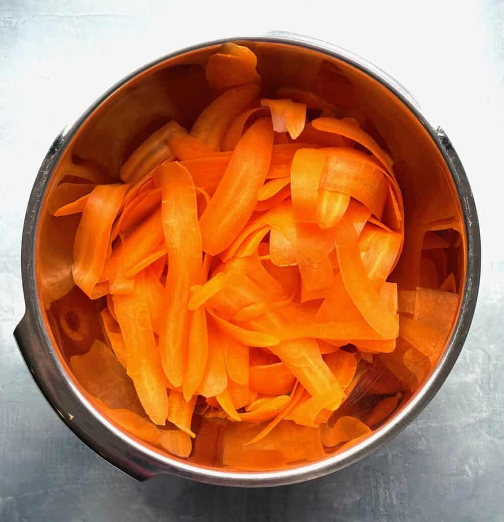 thinly sliced carrots in a metal bowl.