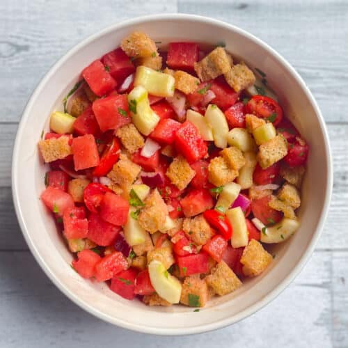 serving bowl containing watermelon panzanella made with sourdough croutons.