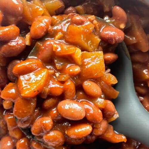 close up of apple baked beans in a ladle.