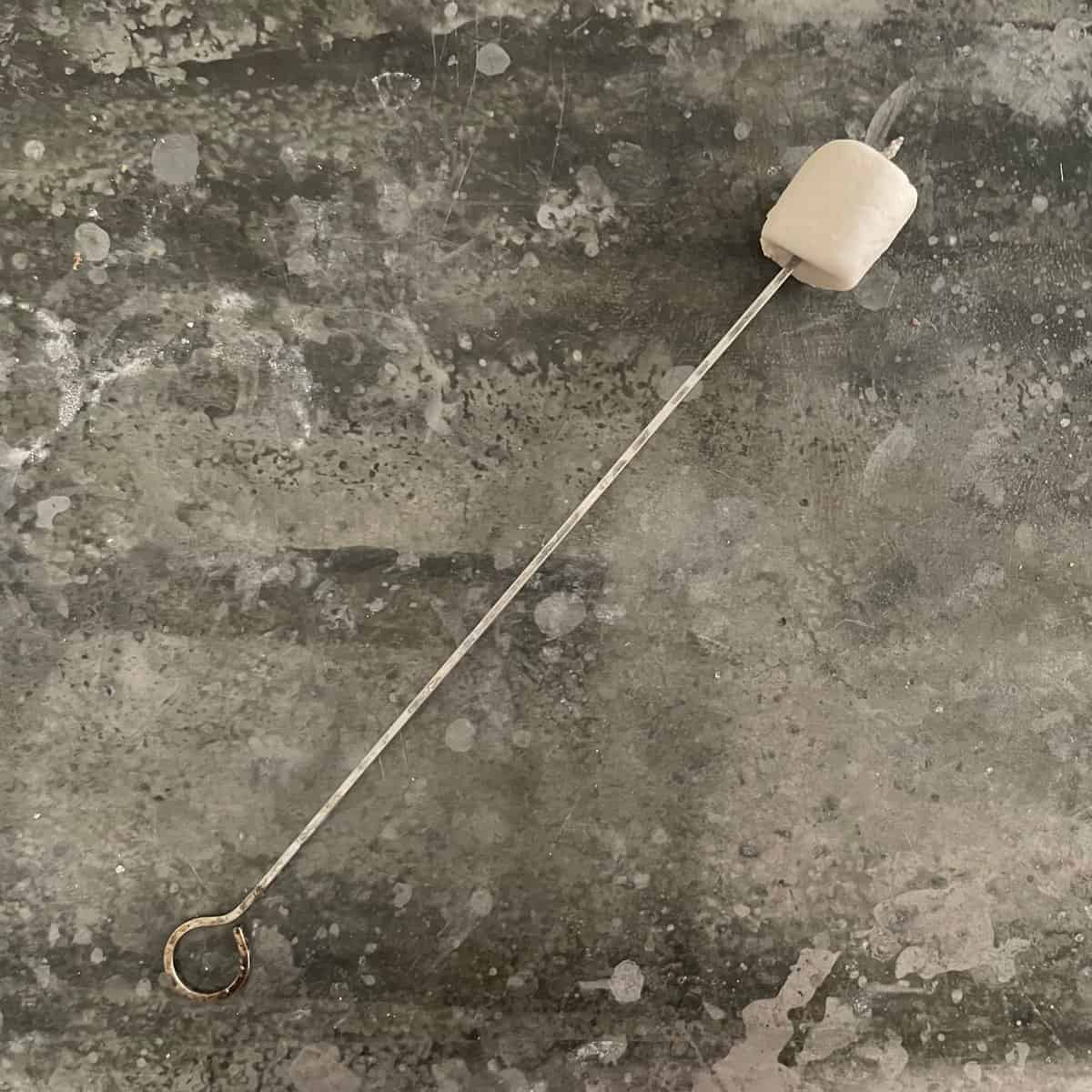 marshmallow on a metal skewer on a metal background.