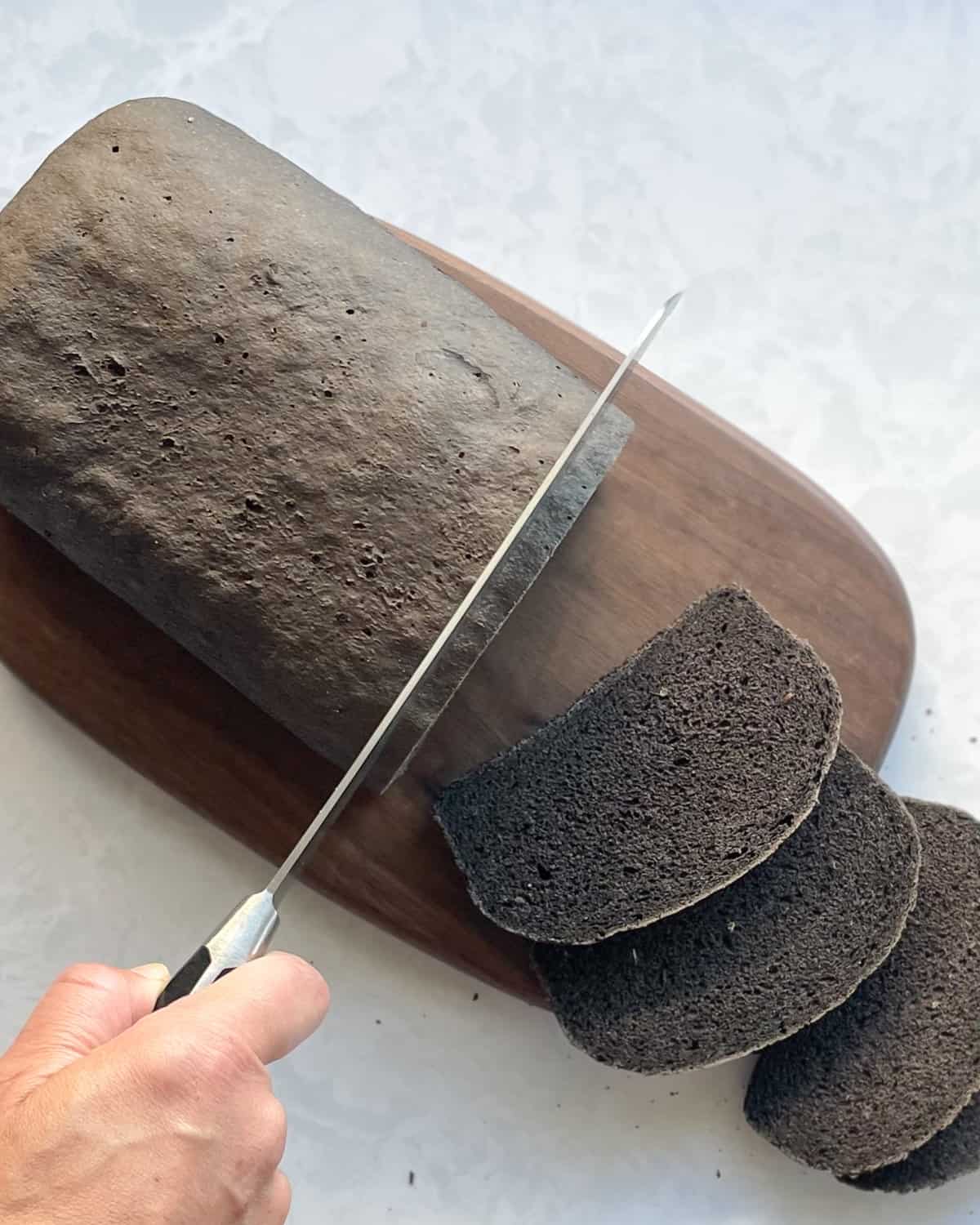 loaf of black russian rye bread being sliced into slices.