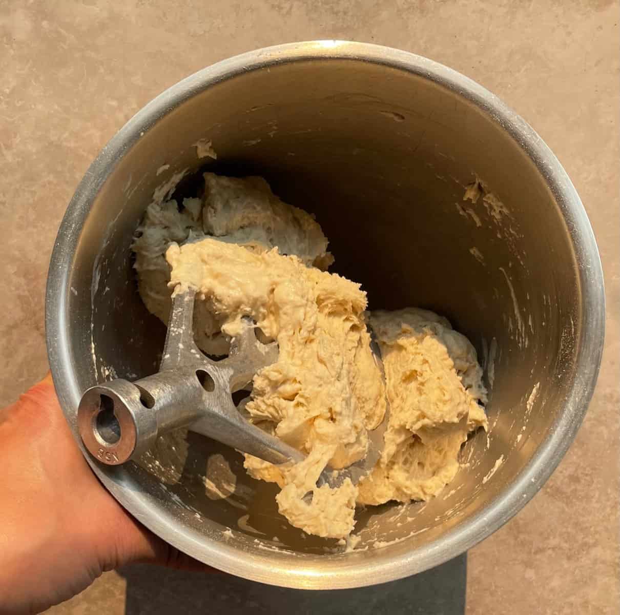 partially mixed ooni pizza dough in a mixing bowl and paddle.