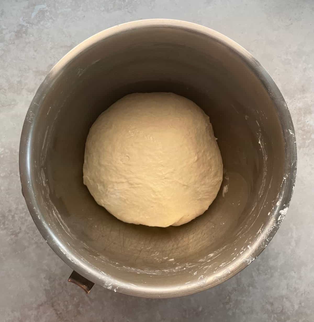 unrisen pizza dough boule in a mixing bowl.