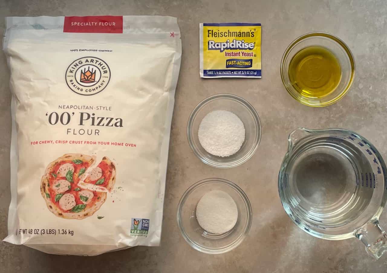 pizza flour and other ingredients to make the ooni pizza dough on a countertop.