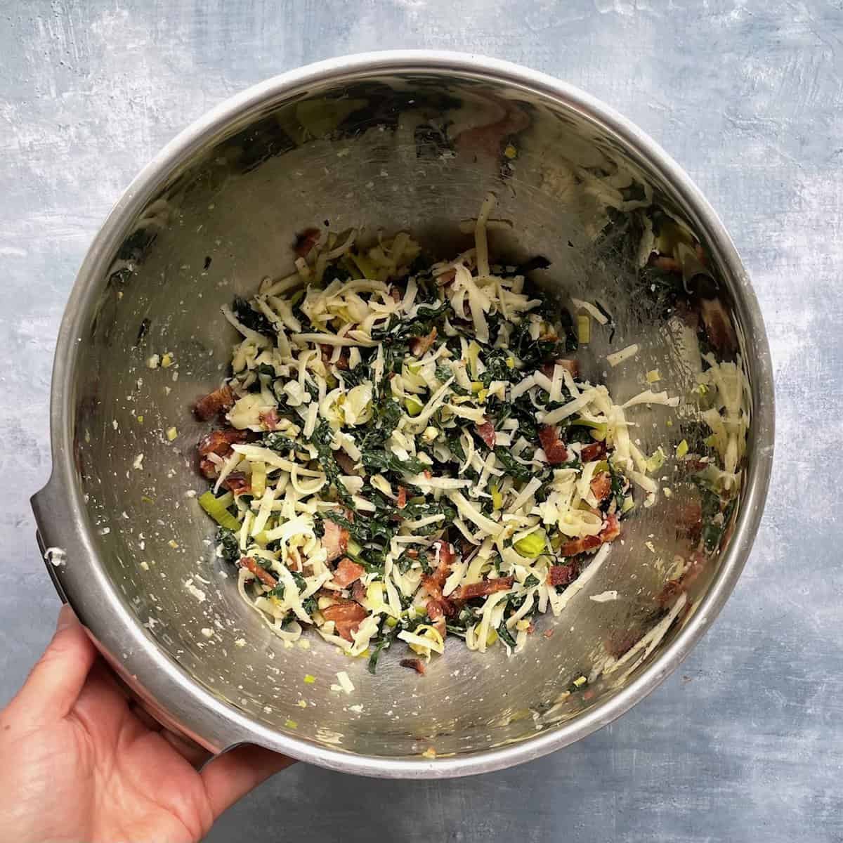 bacon, kale, leek, cheese, and other frittata mix-ins in a metal bowl.
