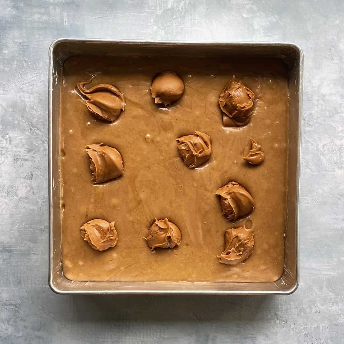 ten scoops of biscoff cookie butter on top of the blondie base in the baking pan.